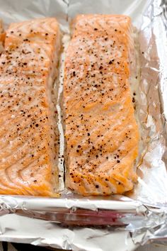 two salmon fillets in foil with seasoning on them, ready to be cooked