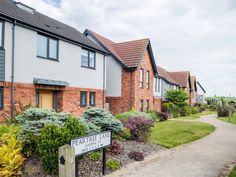 several brick buildings with landscaping around them and a sign in the foreground that says pear tree lane