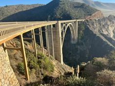 a large bridge spanning over a canyon with mountains in the backgrounds