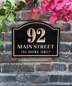 a black and gold address sign on a brick wall