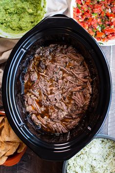 an overhead view of some food in a crock pot with tortilla chips and guacamole on the side