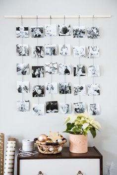 a dresser with pictures hanging on the wall and a potted plant next to it