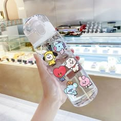 someone holding a water bottle with cartoon stickers on it