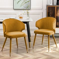 two yellow chairs sitting next to each other near a table