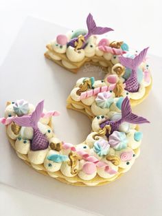 a cake shaped like the letter c with mermaids and seashells on it