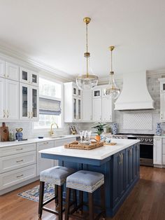 a kitchen with white cabinets and blue island