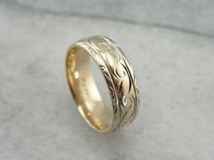 a wedding ring with an intricate design on the outside and inside, sitting on a gray surface