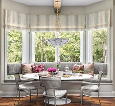 a dining room table with four chairs and a bench in front of a window that overlooks a wooded area