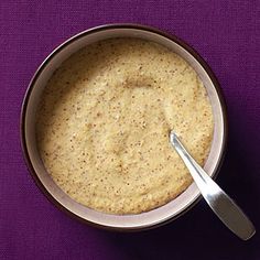 a bowl of food with a spoon in it on a purple table cloth next to a napkin