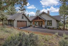 a large house with lots of trees in the front yard and driveway on both sides