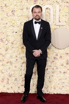 a man in a tuxedo standing on a red carpet