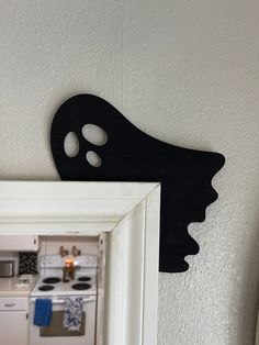 a black mask is hanging on the wall next to a white framed photo with a kitchen in the background