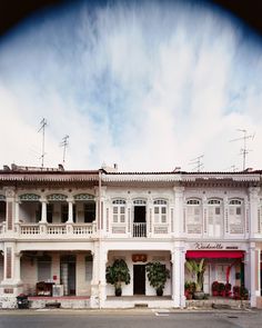 an old white building with balconies and plants on the balconys is seen through a fish eye lens