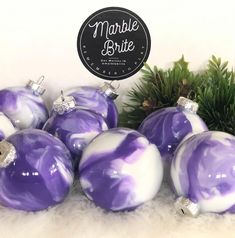 purple and white marbled glass ornaments are displayed on a furnishing area with pine branches