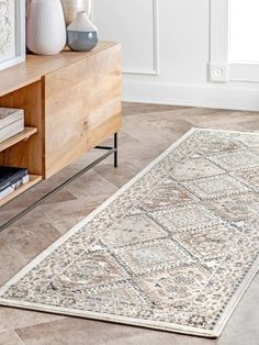 a large rug is on the floor in front of a wooden cabinet and vases