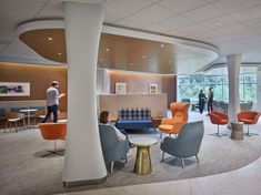 an office lobby with chairs, tables and people walking in the area around them on their cell phones