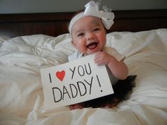 a baby holding a sign that says i love you daddy on it's chest