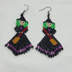 a pair of beaded earrings featuring a witch