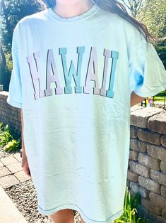 "Such a cute tee for summer! Comfort Colors chambray (light blue) t-shirt with \"HAWAII\" in blue and purple, with a black outline. Model is 5'4\" and wearing a size XL for an oversized look. 100% cotton." Casual Light Blue T-shirt For Summer, Light Blue T-shirt With Letter Print For Spring, Trendy Light Blue Graphic Print T-shirt, Trendy Blue Pre-shrunk T-shirt, Light Blue Relaxed Fit T-shirt With Text Print, Relaxed Fit Light Blue T-shirt With Text Print, Casual Light Blue Summer T-shirt, Light Blue Summer T-shirt For Streetwear, Light Blue T-shirt For Summer Streetwear