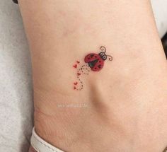 a ladybug tattoo on the side of a woman's ankle with hearts