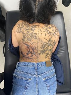 a woman sitting in a chair with her back to the camera and tattoos on her body