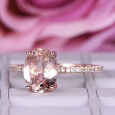 a pink diamond ring sitting on top of a white keyboard with a rose in the background