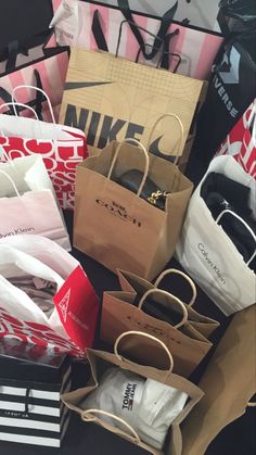 many bags are stacked on top of each other in different colors and shapes, including black, white, pink, red