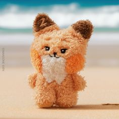 a small stuffed animal sitting on top of a sandy beach