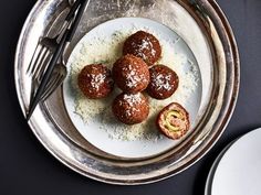 a plate topped with pastries covered in powdered sugar next to a fork and knife