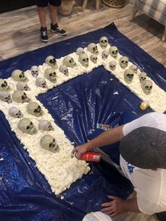 a man is decorating a cake with skulls on it and plastic wrap around the edges