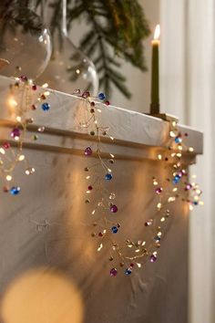 a candle that is on top of a shelf next to a christmas tree and some lights