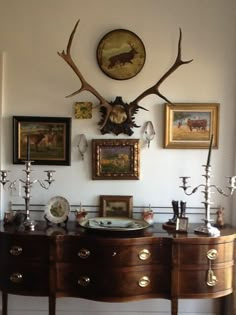 a wall with deer antlers on it and pictures hanging above the dressers in front of them