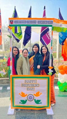 four women standing in front of a sign for happy republic day with flags on it