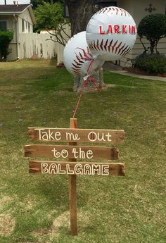 two baseballs are on top of a wooden sign that says take me out to the ballgame