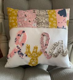 a decorative pillow with the word love spelled out in different colors and letters on it