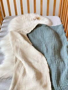 a baby crib with two blankets on top of it and another blanket in the middle