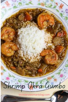 a bowl filled with shrimp and rice on top of a floral table cloth next to silverware