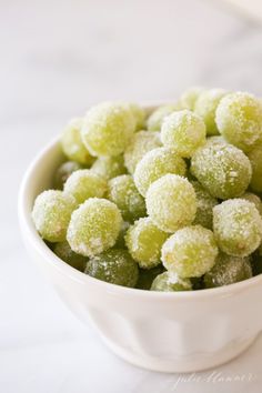 a white bowl filled with green powdered sugar covered candies on top of a table