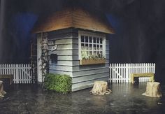 a small wooden house sitting on top of a black floor next to a white picket fence