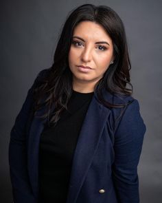 a woman in a blue jacket posing for a photo with her hands on her hips