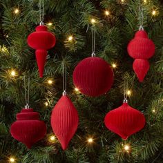 red christmas ornaments hanging from the branches of a tree