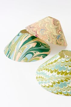 three decorative paper bowls sitting next to each other on a white surface, one with green and blue designs