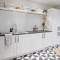 a kitchen with white cabinets and black counter tops, baskets on the wall above the sink