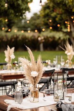 an outdoor dining area with tables, chairs and vases filled with pamodia