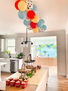 a kitchen filled with lots of balloons and food on top of a wooden cutting board