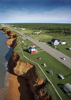 an aerial view of a lighthouse on the edge of a cliff next to the ocean