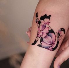 a woman's arm with a cat and flowers tattoo on it