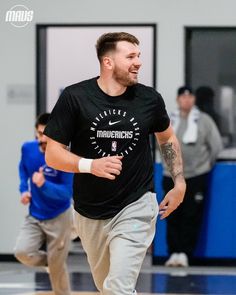 a man running on a basketball court with other men in the background and one wearing a t - shirt that says america