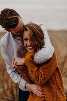 a man and woman hugging each other in an open field