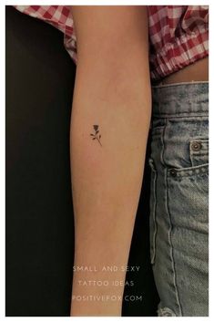 a small flower tattoo on the left forearm and right arm is shown in black ink